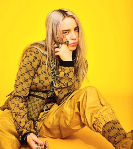 billie in all yello gucci outfit in a yellow back drop 